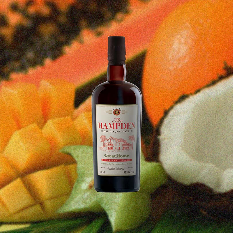 Bottle of Hampden Great House 2024 Distillery Edition over back drop image of coconut and fruits.