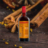 Bottle of Hampden HLCF Classic Pure Single Jamaican Rum over backdrop image of cinnamon on a table.