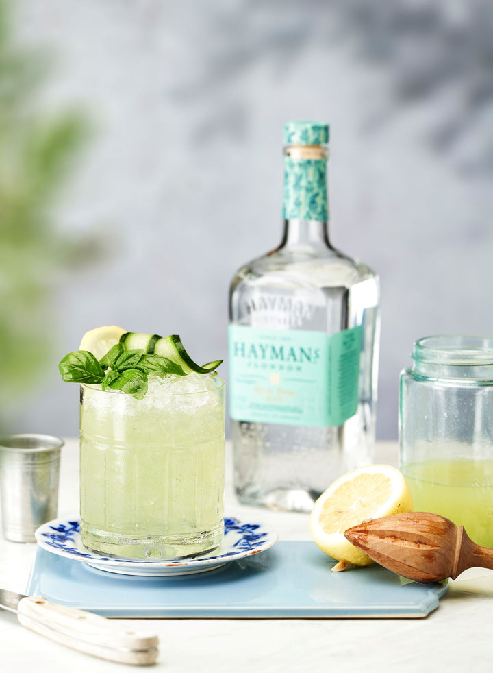 Hayman's gin bottle with a cocktail and lemon on a tray