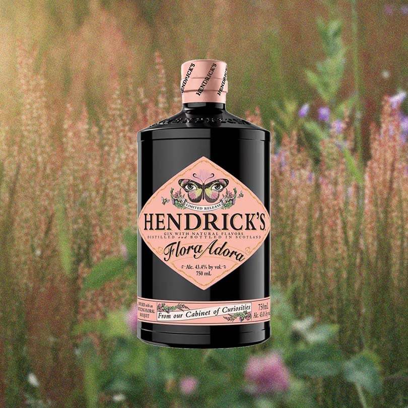 Bottle of Hendrick's Flora Adora Gin over background photo of flowers.