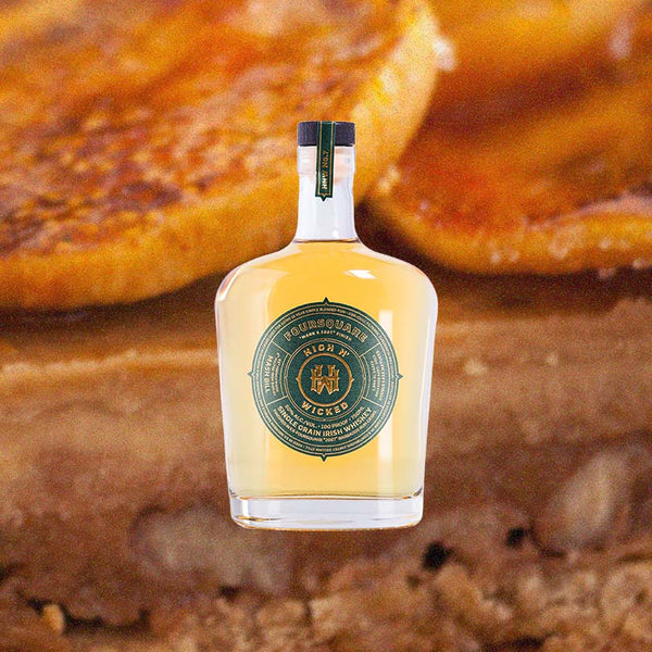 Bottle of High N' Wicked No. 7 "Foursquare Mark X 2007" Rum Cask Finished Single Grain Irish Whiskey over backdrop image of sliced peached on a brownie.