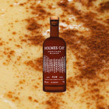 Bottle of Holmes Cay Heritage Blend over back drop of yellow gooey substance with cinnamon.