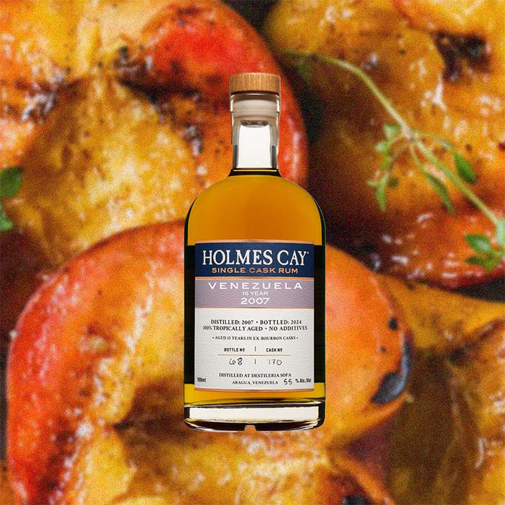 Bottle of Holmes Cay Venezuela 2007 15 Year Rum over back drop image of fruits.