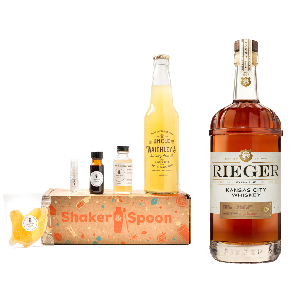 Bottle of Rieger Kansas City Whiskey next to ingredients for cocktail making.