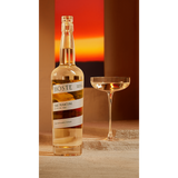 Bottle of Hoste The Martini on a table next to martini glass.