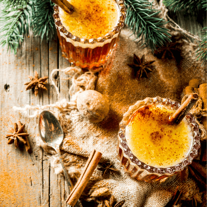 Table with 2 cocktails, spices, and winter decorations.