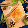Cocktail in a glass mug on a table with cinnamon spice and other festive winter decorations.