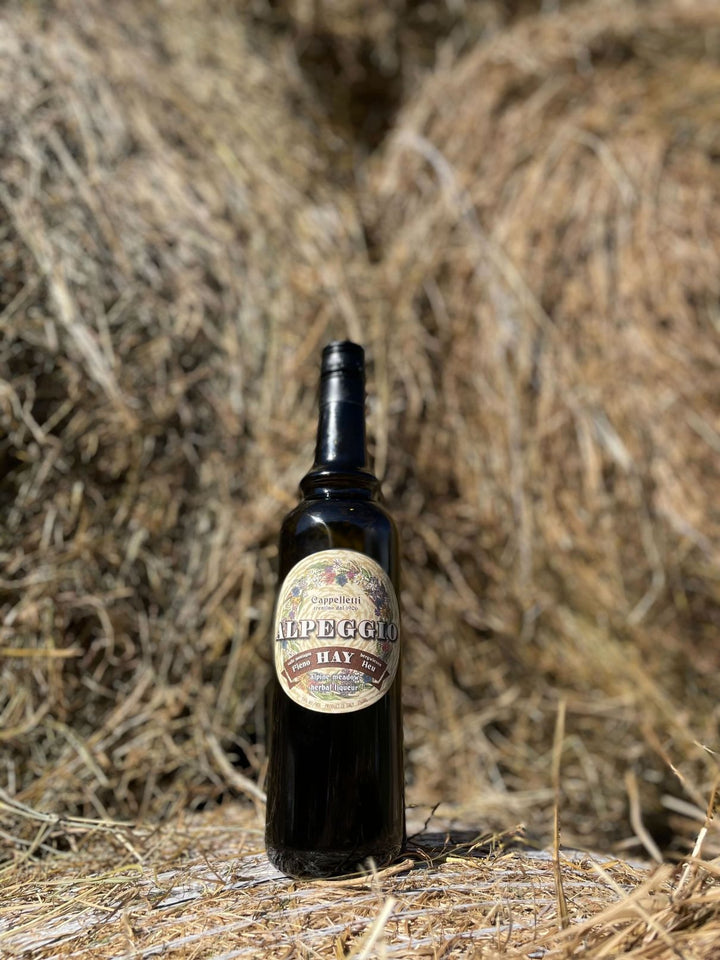 Bottle of Alpeggio Hay Liqueur on a hay background