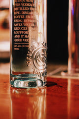 Clear glass bottle with branding on a wooden surface