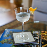 Cocktail in a glass with an orange twist on a coaster, blurred background