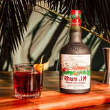 Bottle of Rhum J.M. with a cocktail on a wooden table