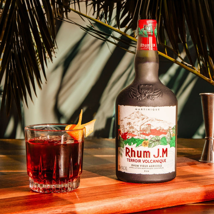 Bottle of Rhum J.M. with a cocktail on a wooden table