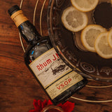 Bottle of Rhum JN VSOP rum with lemon slices on a wooden surface