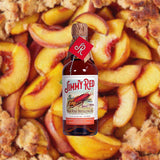 Bottle Image ofJimmy Red Straight Bourbon Whiskey Peach Brandy Cask Finish set against backdrop of peach cobbler