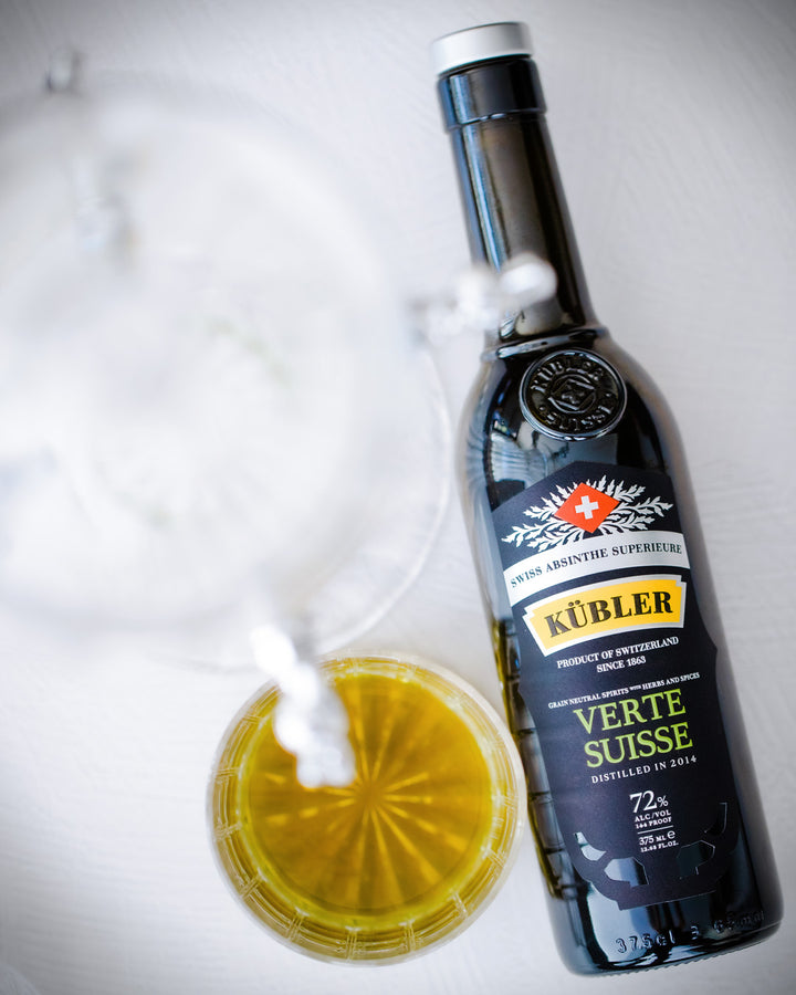 Bottle of Kübler Verte Suisse with a small container of yellow liquid on a white background