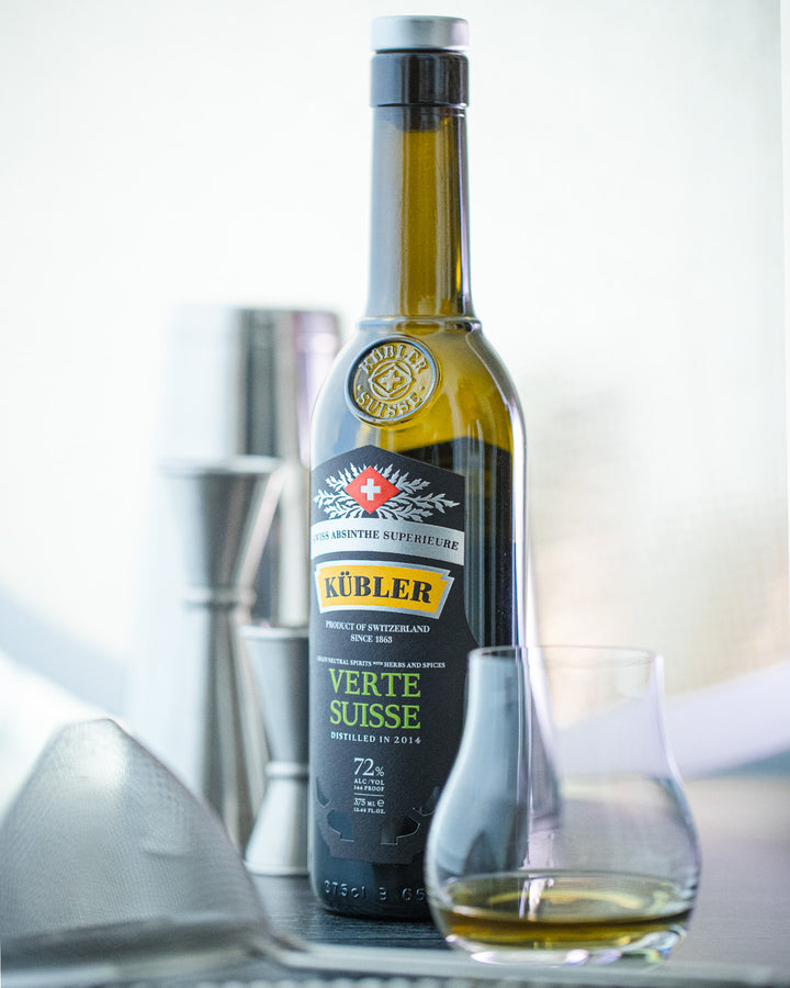 Bottle of Kubler Verte Suisse whiskey on a reflective surface with a blurred background