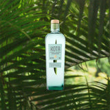 A bottle of Kota Pandan Liqueur over backdrop of green plant leaves.