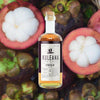 A bottle of Kuleana Rum Works Hokulei Rum against a backdrop of freshly picked mangosteens, some whole, some sliced.