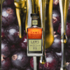 Bottle of Laws San Luis Valley Straight Rye over backdrop image of purple fruit.