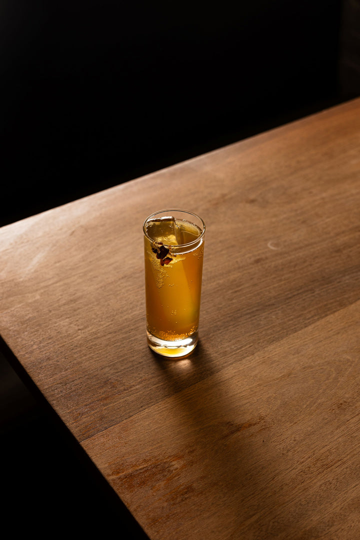Glass of amber liquid on a wooden surface with a dark background