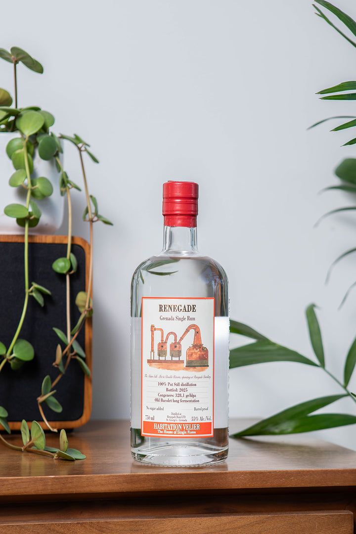 Bottle of Renegade Rum on a wooden surface with plants in the background