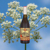 Bottle of Legendre Herbsaint Original Liqueur over backdrop of blue sky and flower.