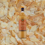 A bottle of Liber & Co. Almond Orgeat Syrup with a label showcasing the brand and product name, set against a background of sliced almonds.