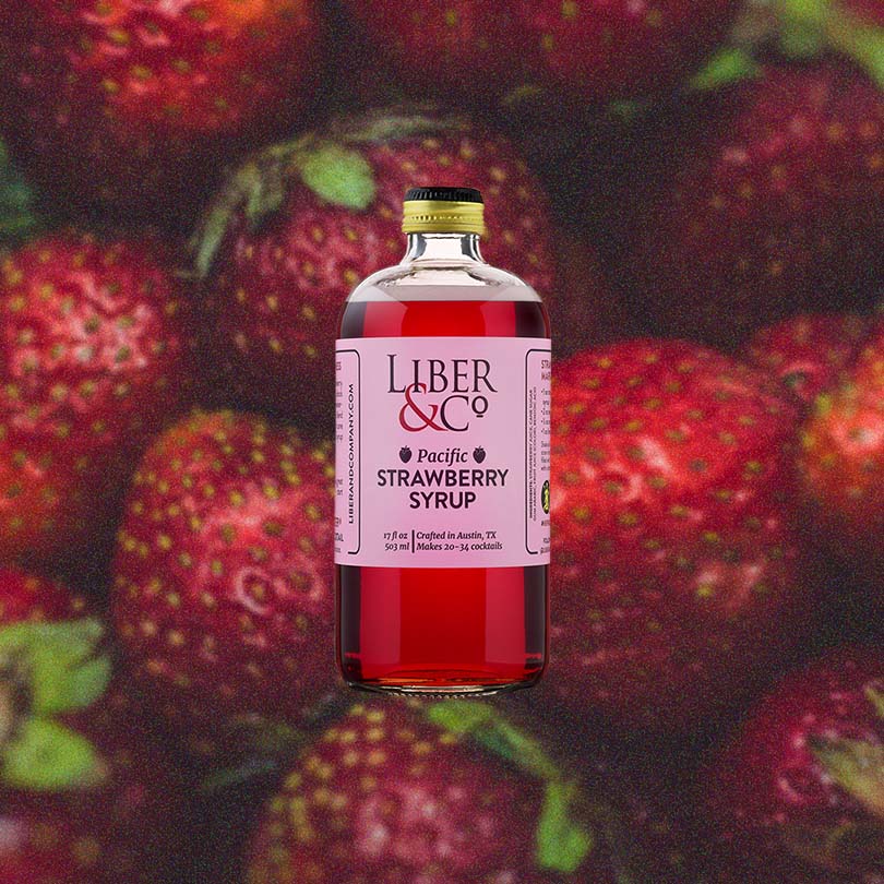 Bottle of Liber & Co. Pacific Strawberry Syrup over backdrop image of Strawberries.