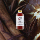 A small premium bottle of warm red liquid, the label reads: Liber & Co Old Fashioned Cocktail Syrup. Against a macro shot of cinnamon, star anise, and orange.