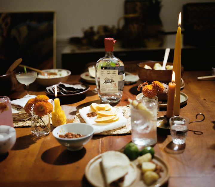 Dinner table with food, drinks, and candles in a cozy setting