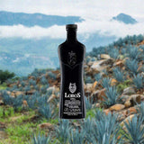 Bottle of Lobos 1707 Mezcal Artesanal over backdrop of blue agabve on a mountain side.