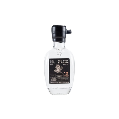 A mini sized 200ml bottle of The Lost Explorer Mezcal. The top is dipped in black wax, and the label is black with gold detailing.  It reads Mezcal Artesanal Hecho in Mexico.  10 Agave Age in Years.