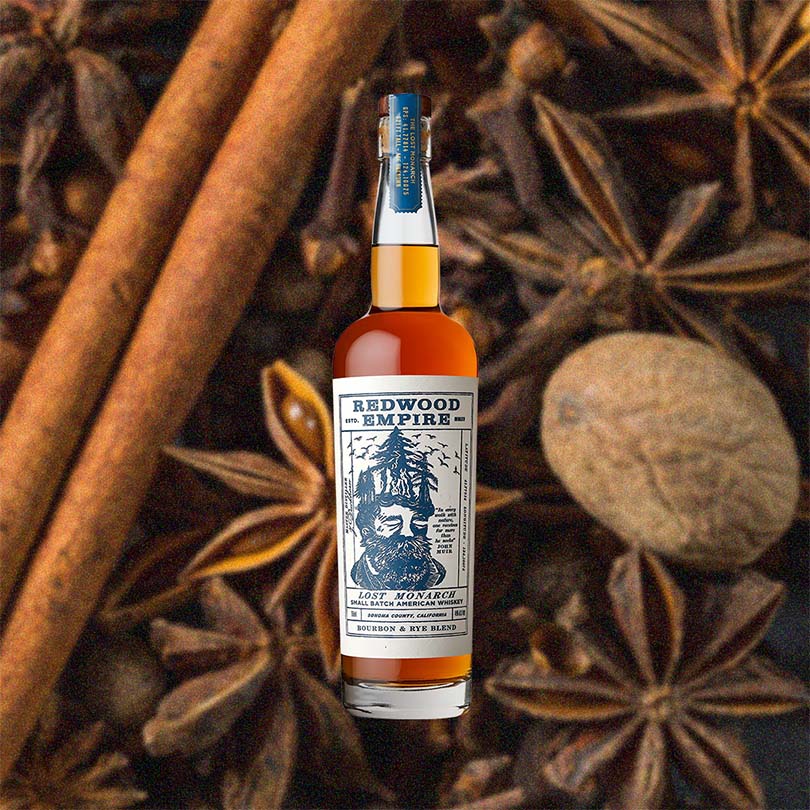 Bottle of Redwood Empire Lost Monarch Small Batch American Whiskey over backdrop image of spices.