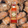 Bottle of Luxardo Amaretto di Saschira Liqueur over backdrop of sugary almonds or pecans.
