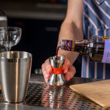 Barista pouring syrup into a portafilter on a bar with a blurred background