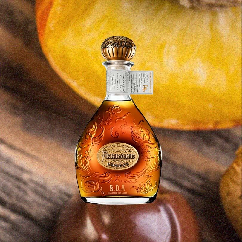 Bottle of Ferrand S.D.A. Selection Des Anges Cognac over back drop of a peach.