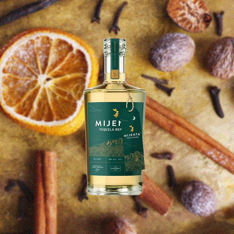 Bottle of Mijenta Reposado Tequila over backdrop of spices.