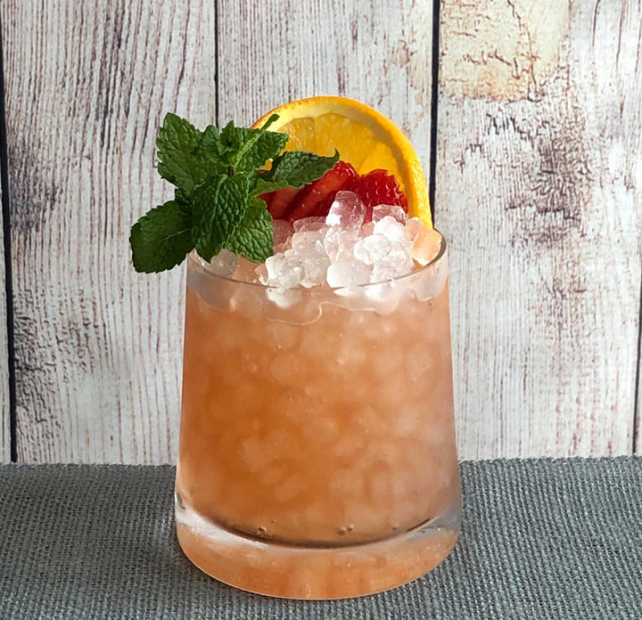 Cocktail with ice, orange slice, and mint on a wooden surface