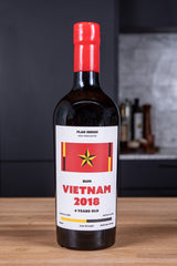 Bottle of Vietnam 2018 rum with a red cap on a wooden surface.