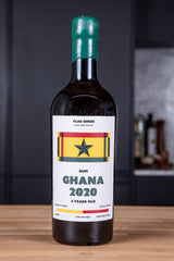 Bottle of Rum Ghana 2020 with a flag label on a wooden surface.