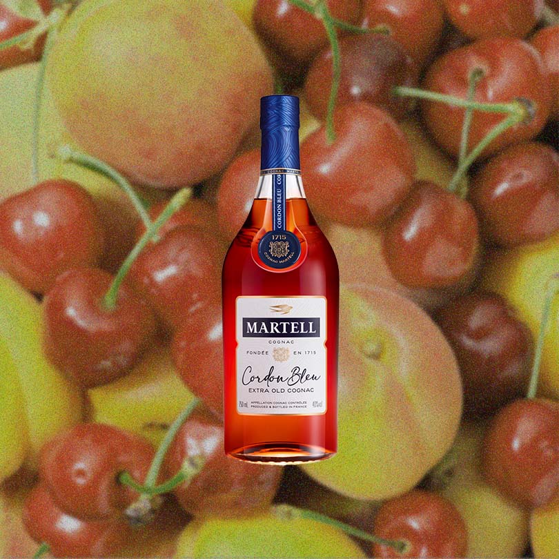 Bottle of Martell Cordon Bleu Cognac over backdrop image of fruit.