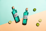 Two bottles of Rigatoni Blue Liqueur on a colorful background with limes.