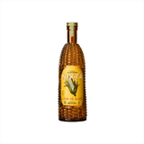 A bottle of rich yellow looking alcohol. The bottle itself has the shape and texture of a corn cob. The label reads: Nixta Licor de Elote. Hecho En Mexico.