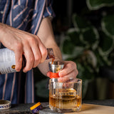 Person pouring a liquid from a bottle into a glass with a blurred background