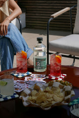 Outdoor setting with drinks, snacks, and playing cards on a table.