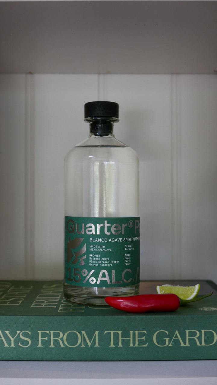 Bottle of Quarter Proof Alc on a book with a lime and red pepper