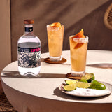 Two cocktails with orange slices and limes on a plate, next to a bottle of Espolón tequila.