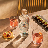 Mayenda tequila bottle with two cocktails and snacks on a table