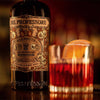 A close-up shot of the bottle of Del Professore Vermouth di Torino Rosso with a freshly-made negroni, orange slice included, right next to it.