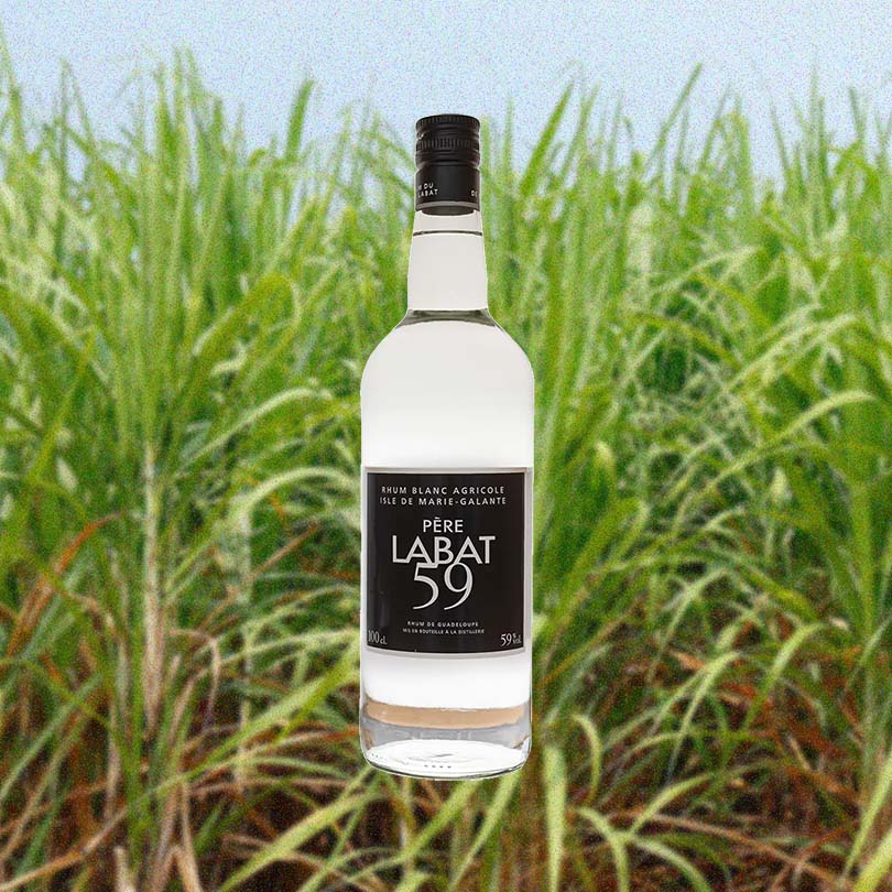 Bottle of Pere Labat 59 Rhum Agricole over backdrop of a green field.